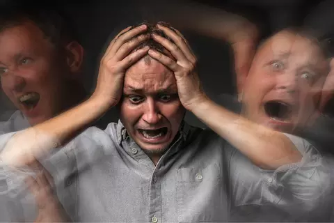 Afbeelding van een schreeuwende man met de handen op het hoofd