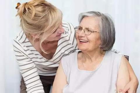 Afbeelding van een jongere en oudere vrouw die naar elkaar glimlachen